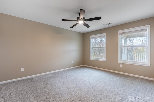 carpeted spare room featuring a ceiling fan, visible vents, and baseboards