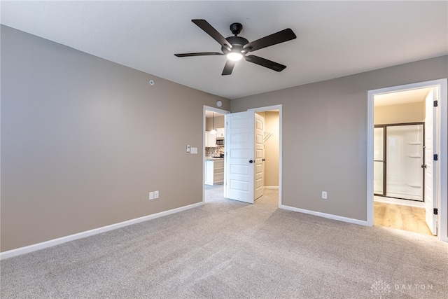 unfurnished bedroom with light colored carpet, connected bathroom, a spacious closet, and baseboards