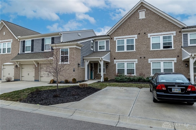 view of property featuring driveway, an attached garage, and brick siding