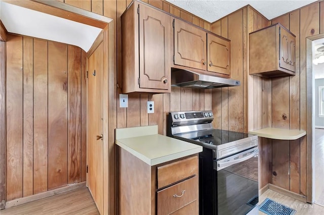 543 W Market St, Germantown, OH 45327 - kitchen with electric range, light wood-style floors, under cabinet range hood, light countertops, and wood walls