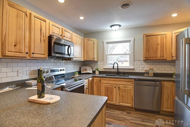 kitchen featuring stainless steel appliances, dark countertops, visible vents, and a sink