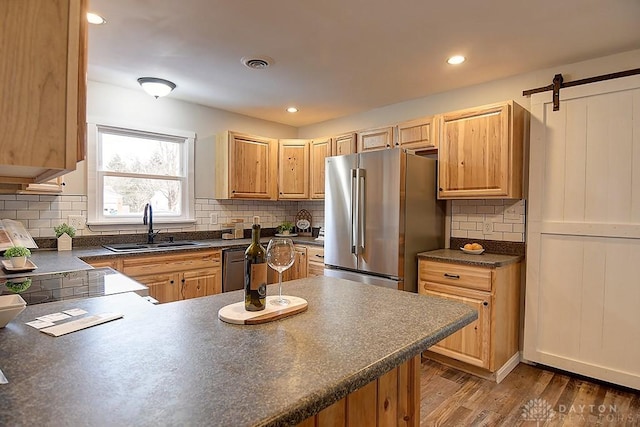 kitchen with high end refrigerator, dark countertops, visible vents, a sink, and dishwashing machine