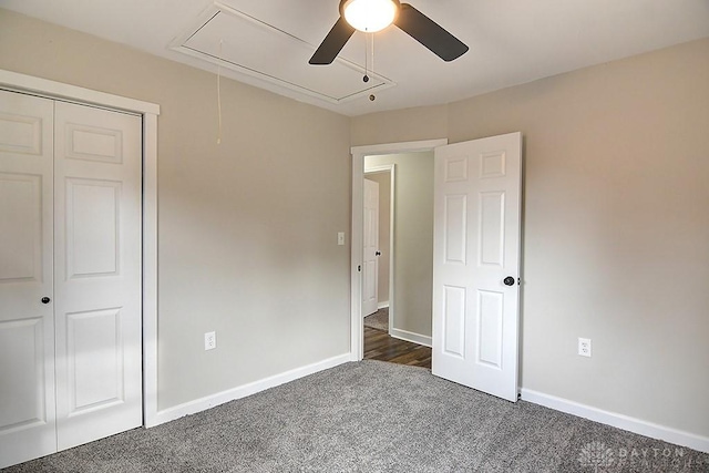 unfurnished bedroom featuring ceiling fan, dark carpet, attic access, and baseboards