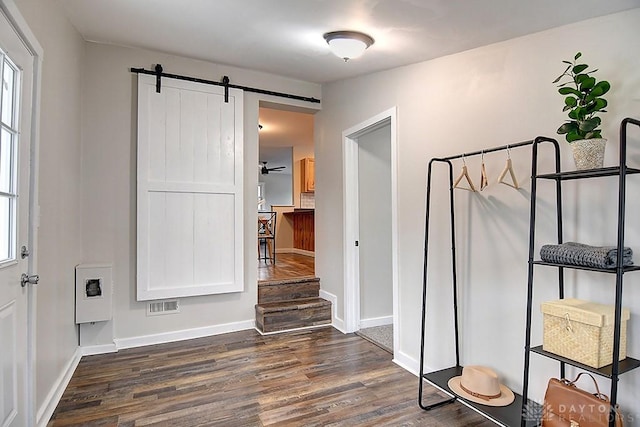 hallway featuring baseboards, a barn door, visible vents, and dark wood-type flooring