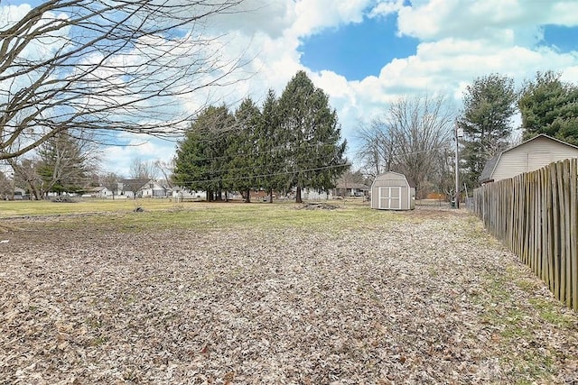 view of yard featuring a storage unit, an outdoor structure, and fence