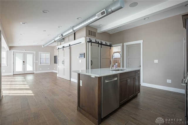 kitchen with a barn door, dark wood-type flooring, a sink, open floor plan, and dishwasher