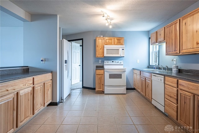 kitchen with a textured ceiling, dark countertops, white appliances, and a sink