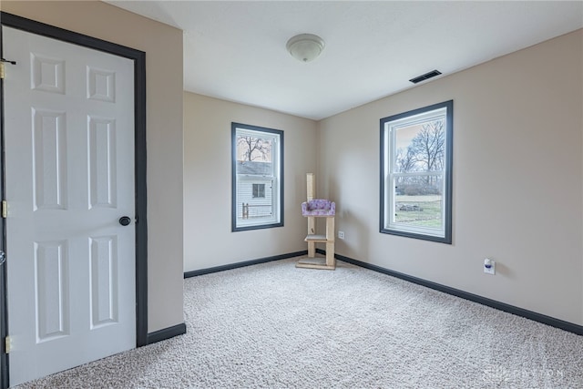 spare room featuring carpet flooring, baseboards, and visible vents