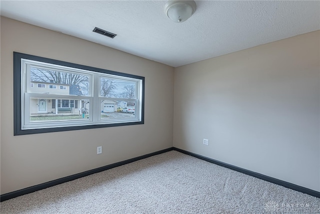 carpeted empty room with visible vents, a textured ceiling, and baseboards