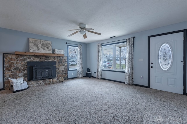 unfurnished living room with a textured ceiling, carpet floors, and baseboards