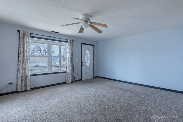 carpeted spare room featuring visible vents, baseboards, ceiling fan, and a textured ceiling