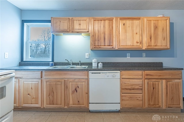 kitchen featuring light brown cabinetry, white appliances, and a sink