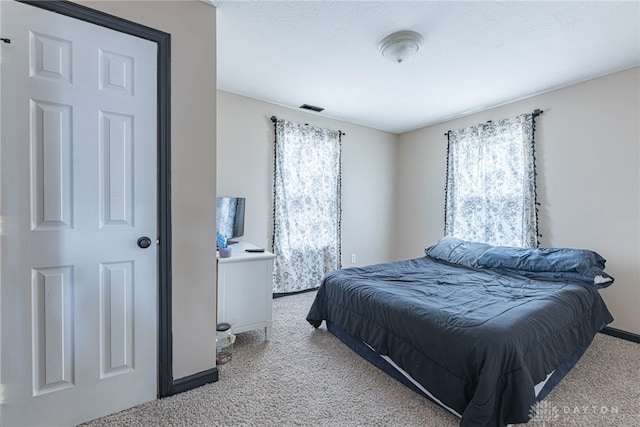 bedroom with multiple windows, visible vents, and light carpet