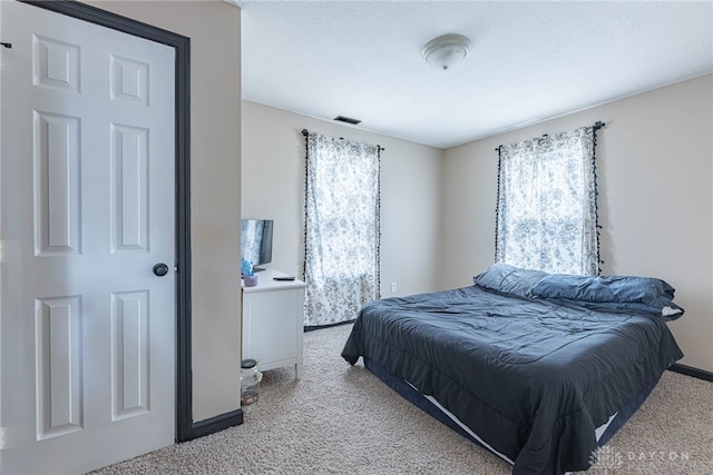 bedroom featuring light colored carpet, visible vents, baseboards, and multiple windows