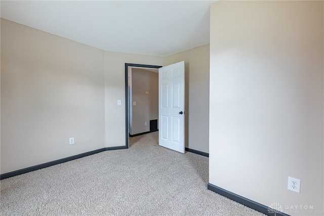 unfurnished room with baseboards and light colored carpet