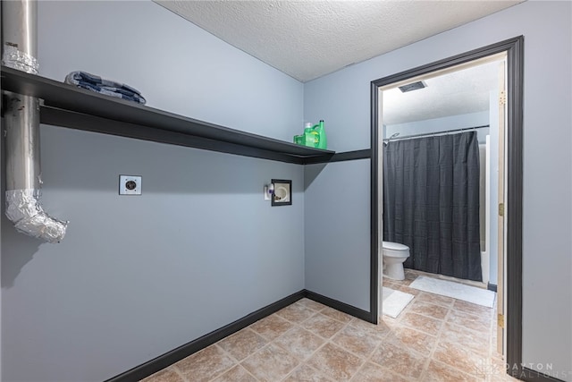 washroom with a textured ceiling, electric dryer hookup, visible vents, baseboards, and laundry area