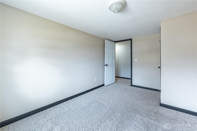 carpeted empty room with a textured ceiling and baseboards