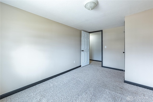 carpeted empty room featuring baseboards