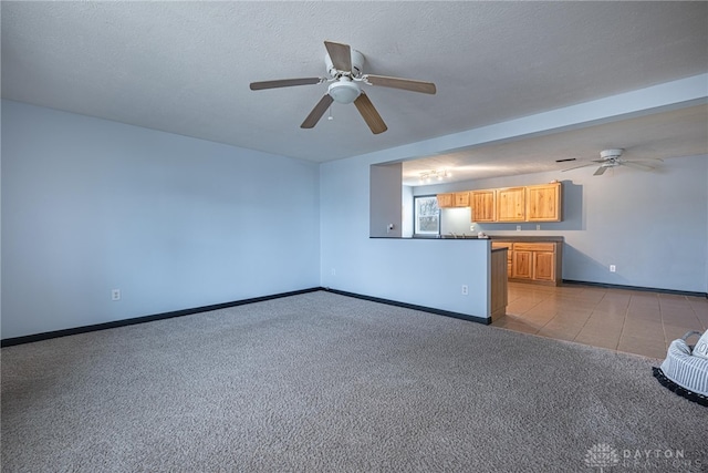 unfurnished living room with baseboards, carpet floors, ceiling fan, tile patterned flooring, and a textured ceiling