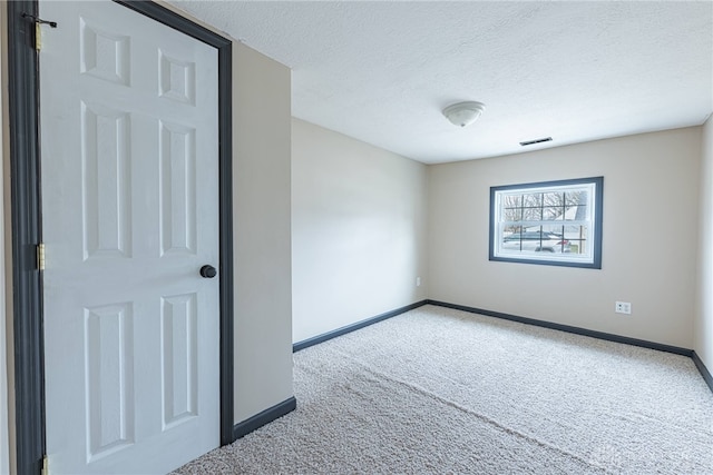 carpeted spare room featuring baseboards, visible vents, and a textured ceiling