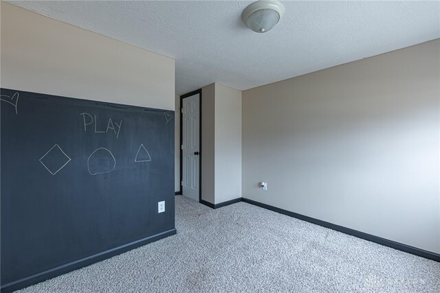 spare room featuring a textured ceiling, carpet, and baseboards