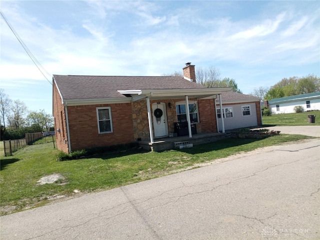 view of front of house featuring a porch, a front yard, a chimney, roof with shingles, and fence