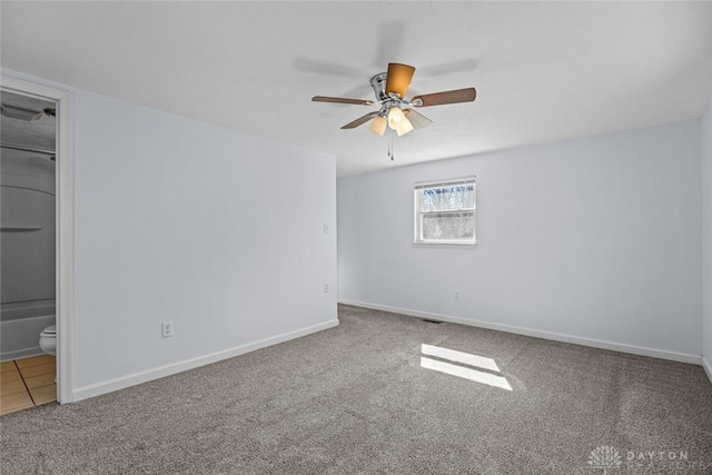 carpeted empty room with a ceiling fan and baseboards