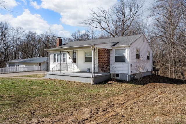 bungalow-style house featuring a front lawn, a chimney, and fence