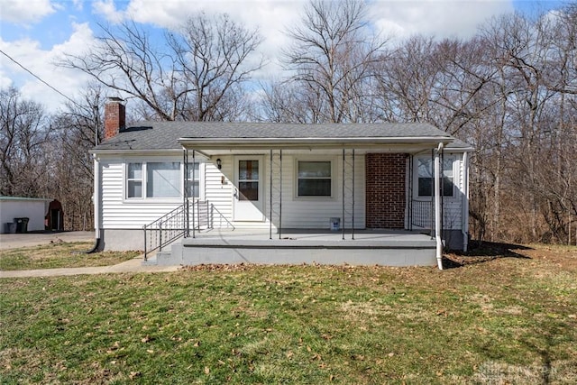 bungalow-style home featuring a porch, a front yard, and a chimney