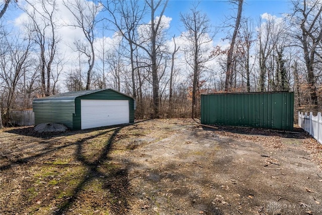 view of yard featuring an outbuilding, a detached garage, and fence