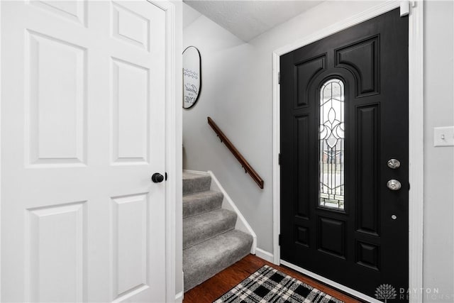 foyer entrance featuring stairs, dark wood finished floors, and baseboards