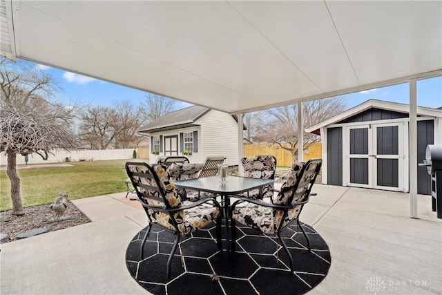 view of patio with an outbuilding, outdoor dining area, and fence