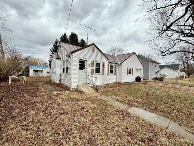 bungalow-style home featuring fence, metal roof, and a front yard