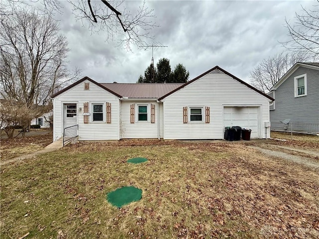 view of front facade with an attached garage, dirt driveway, a front lawn, and metal roof