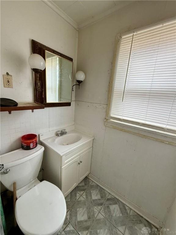 half bath featuring toilet, vanity, and crown molding