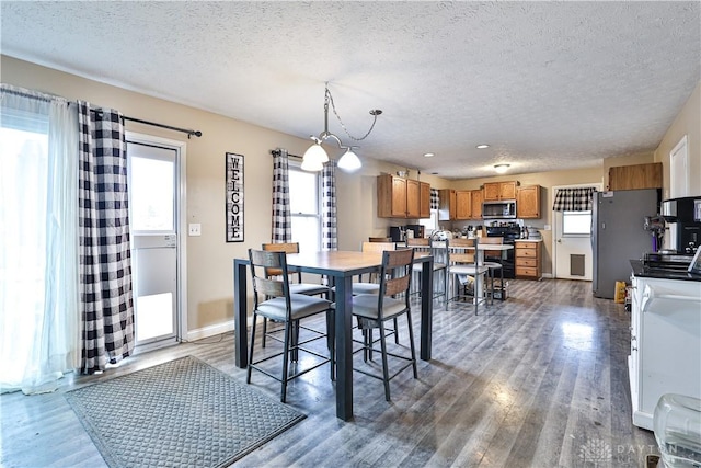 dining space featuring a textured ceiling, wood finished floors, a wealth of natural light, and baseboards