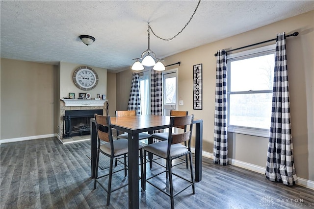 dining space with dark wood-style floors, a tile fireplace, a healthy amount of sunlight, and baseboards