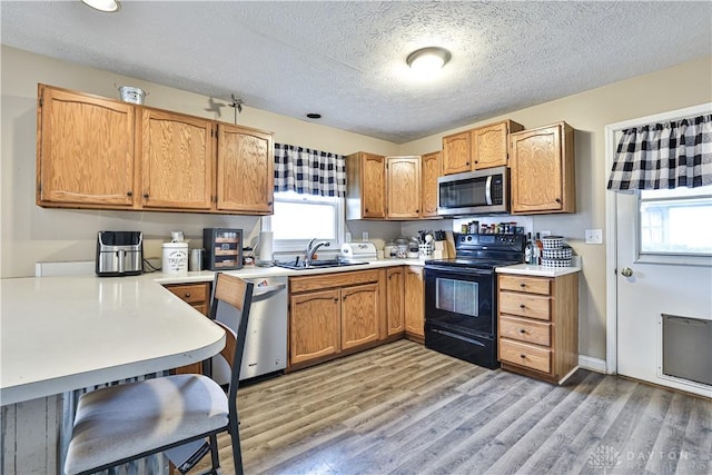 kitchen featuring light countertops, appliances with stainless steel finishes, light wood-type flooring, and a sink