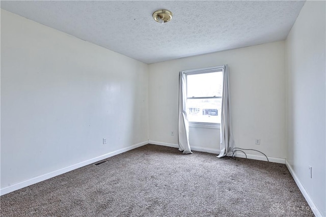 unfurnished room with carpet, a textured ceiling, visible vents, and baseboards