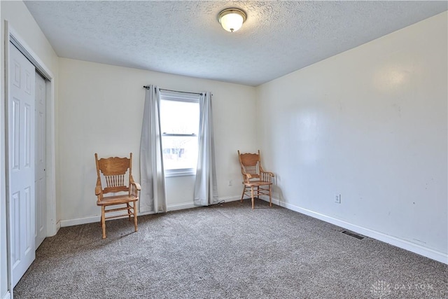 unfurnished room with carpet, a textured ceiling, visible vents, and baseboards