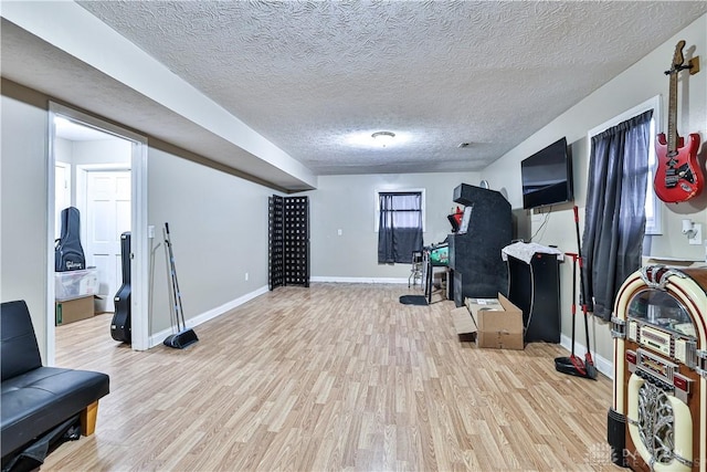 exercise area featuring a textured ceiling, baseboards, and wood finished floors