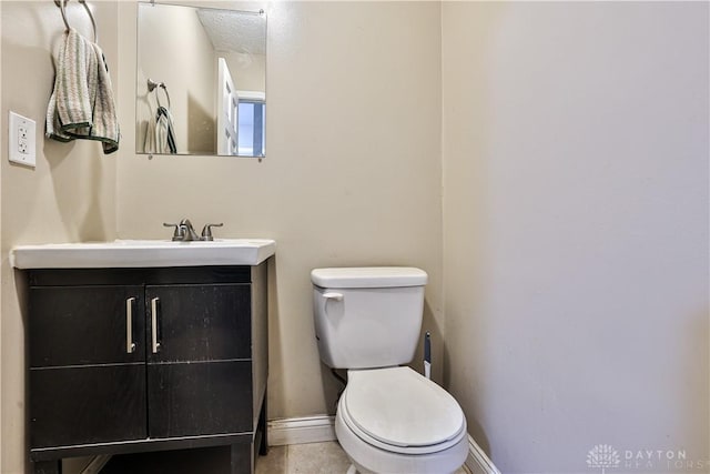 bathroom featuring toilet, baseboards, and vanity