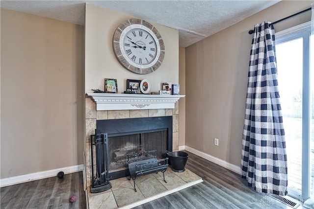 details with a textured ceiling, baseboards, wood finished floors, and a tile fireplace