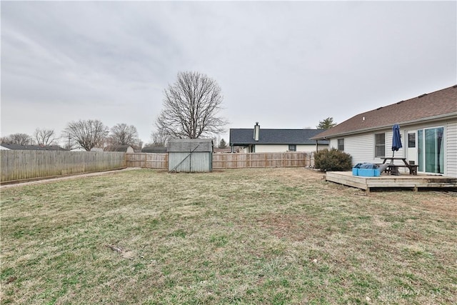 view of yard with a fenced backyard, an outdoor structure, a wooden deck, and a shed