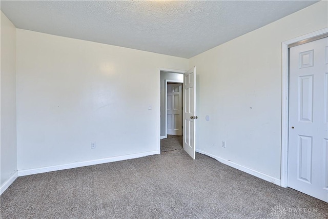 carpeted empty room with a textured ceiling and baseboards