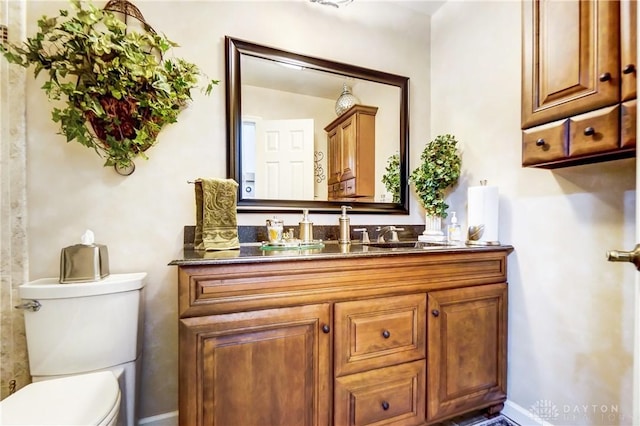 bathroom featuring toilet, baseboards, and vanity