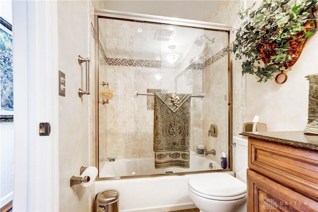 bathroom featuring toilet, combined bath / shower with glass door, and vanity