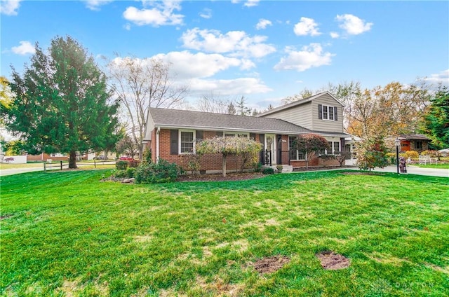 view of front facade featuring fence, a front lawn, and brick siding