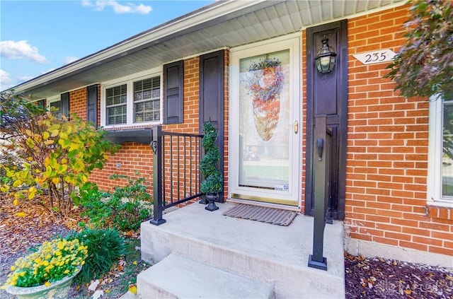 entrance to property featuring covered porch and brick siding