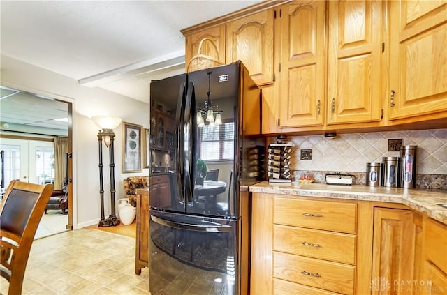 kitchen with a healthy amount of sunlight, tasteful backsplash, light countertops, and freestanding refrigerator